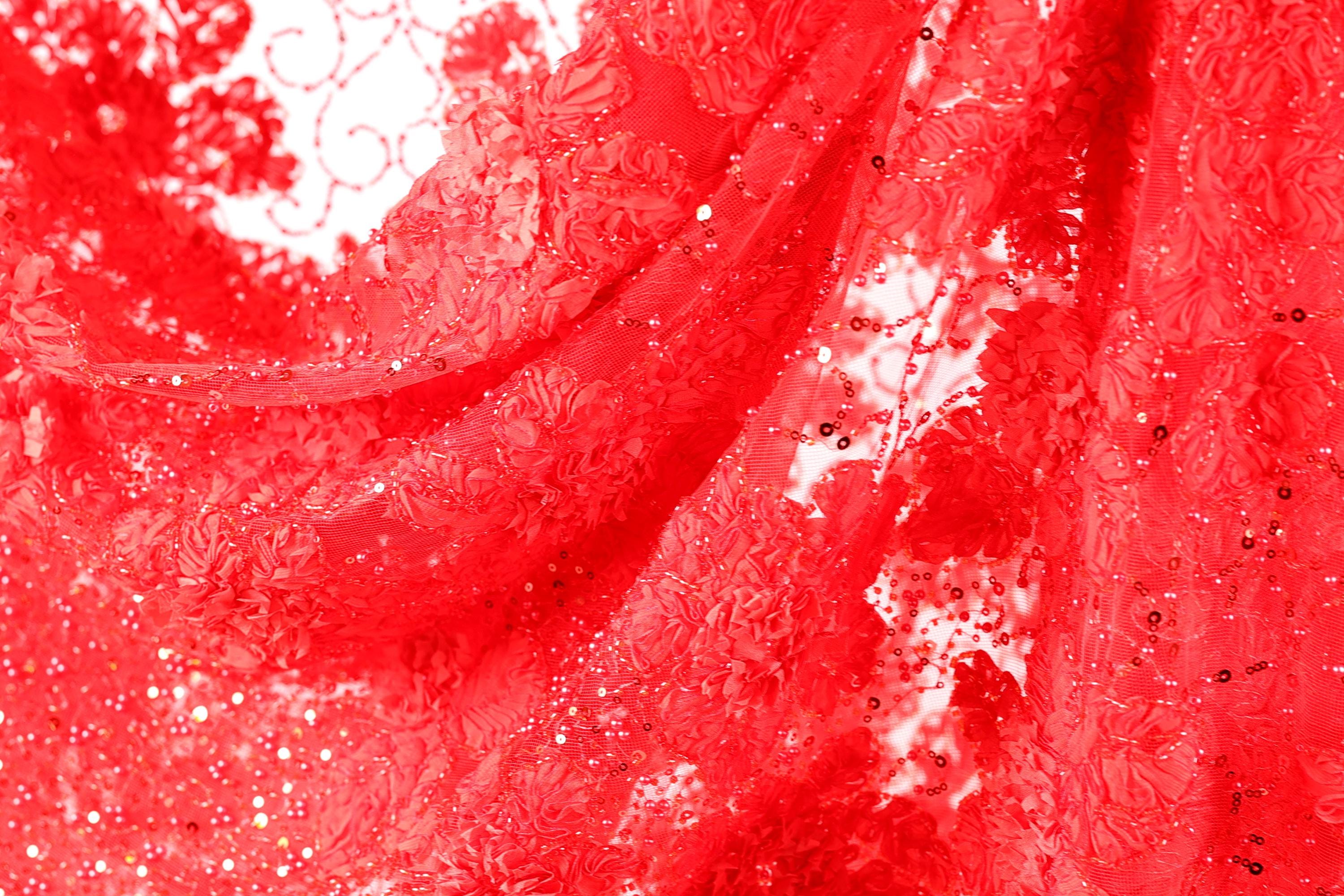 The image is a close-up of a red fabric with a floral pattern, featuring a lot of small details and textures.