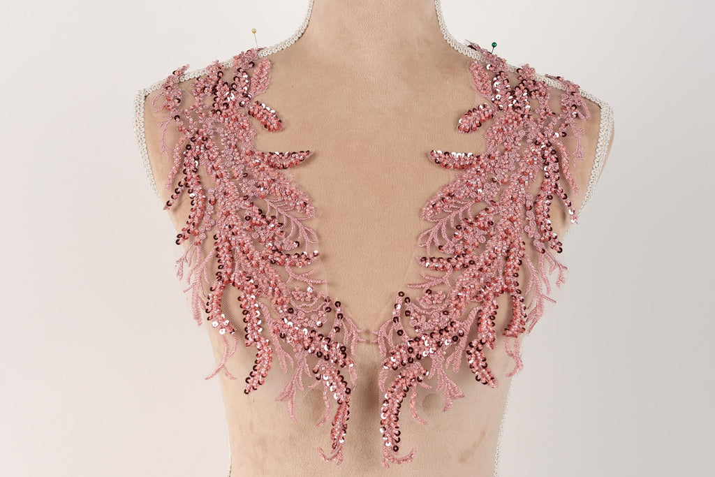A mannequin wearing a pink sequin and lace dress with a v-neck design.