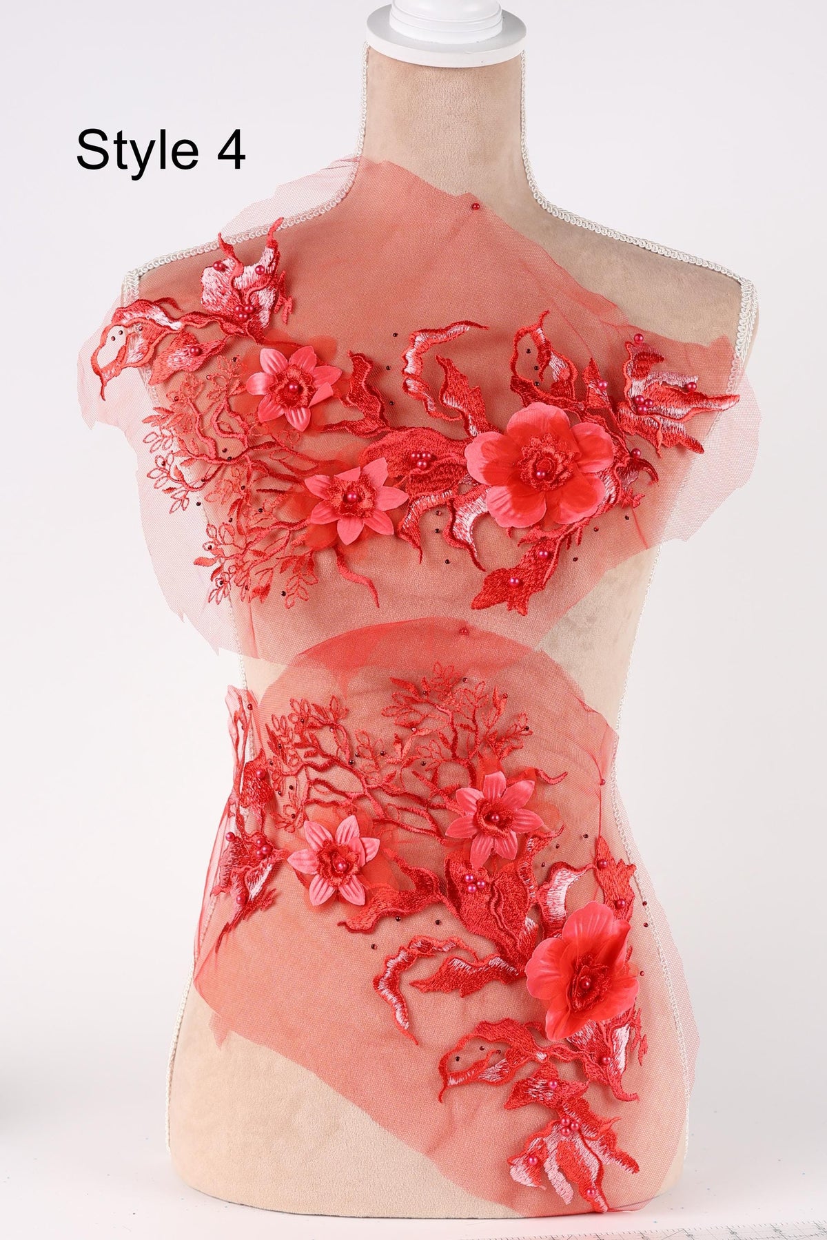A mannequin wearing a red dress with intricate floral embroidery on the bodice and skirt.