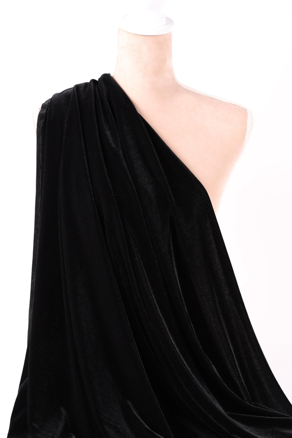 A close-up view of a black velvet fabric, with a white object partially visible in the background.
