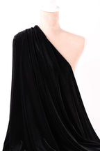 A close-up view of a black velvet fabric, with a white object partially visible in the background.