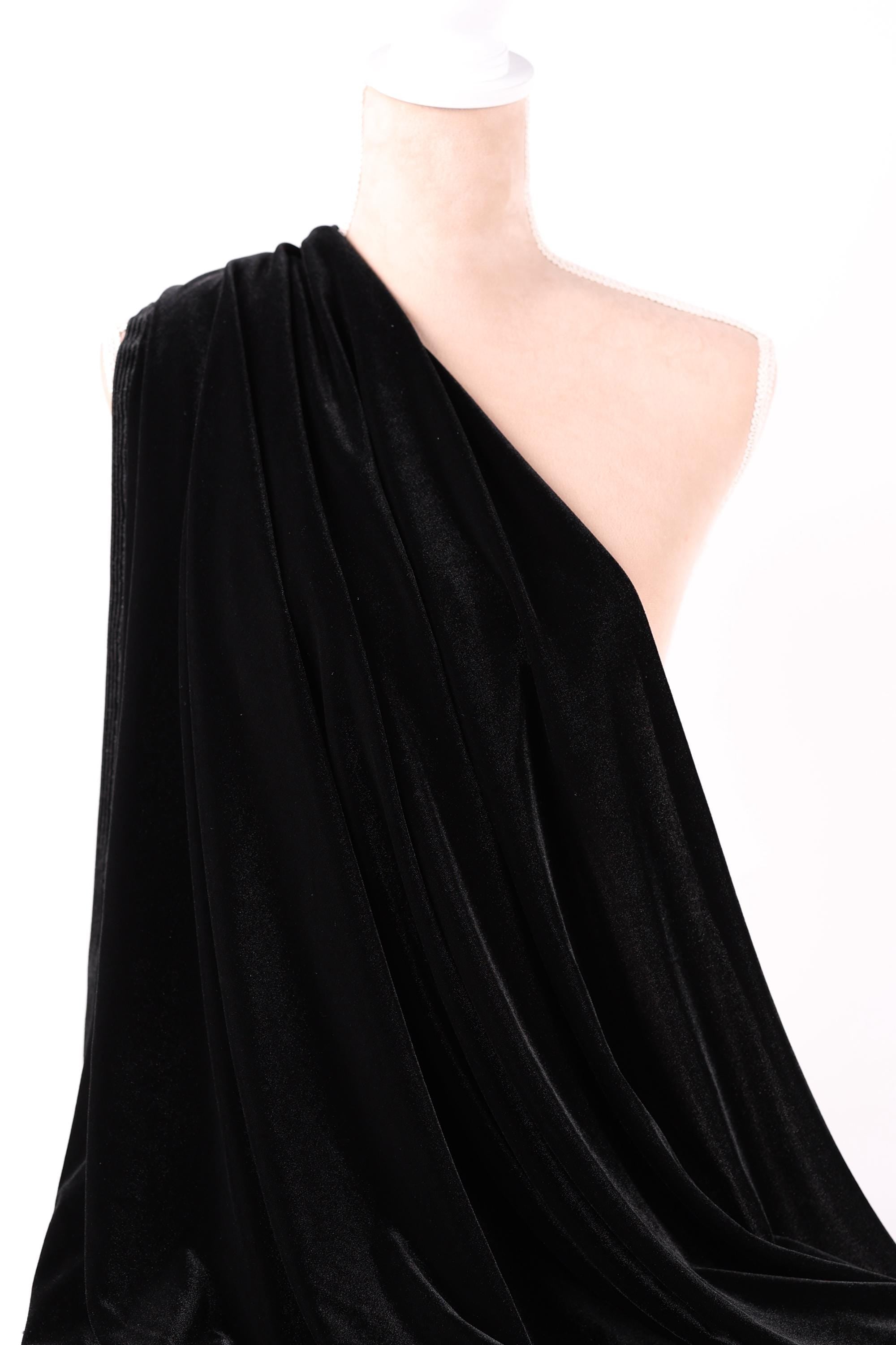 A close-up view of a black velvet fabric, with a white object partially visible in the background.