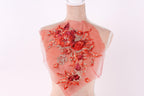 A mannequin with a red floral embroidered on its back, featuring a variety of red and orange flowers and leaves.