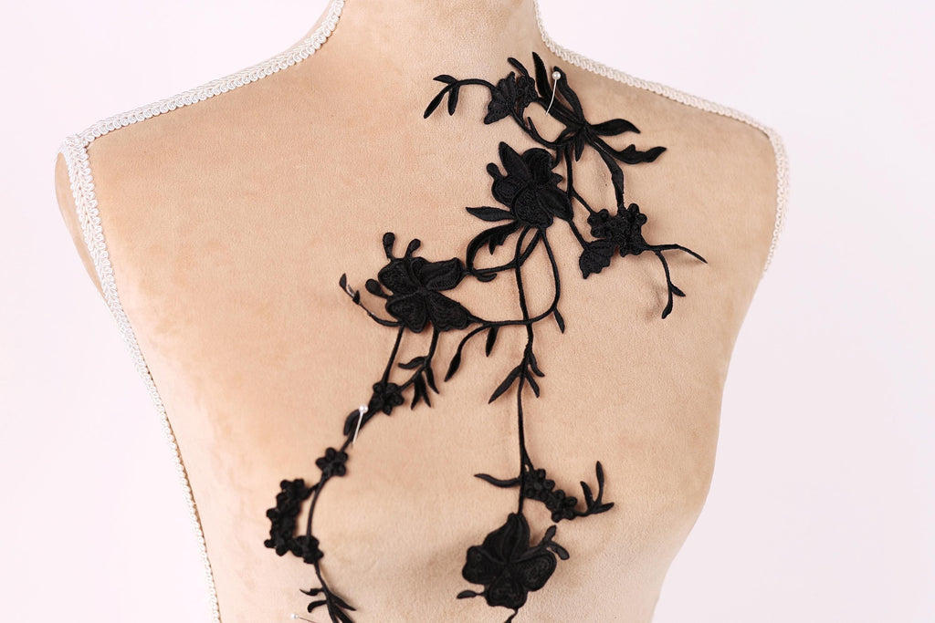 A mannequin with a black lace design on its back, featuring a floral pattern.