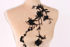 A mannequin with a black lace design on its back, featuring a floral pattern.