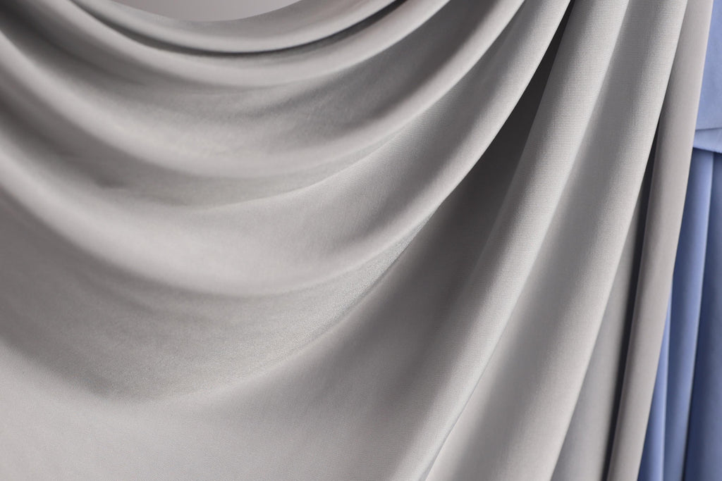 a close-up view of a gray fabric, possibly a curtain or textile, with a soft, flowing texture.
