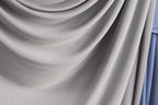 a close-up view of a gray fabric, possibly a curtain or textile, with a soft, flowing texture.