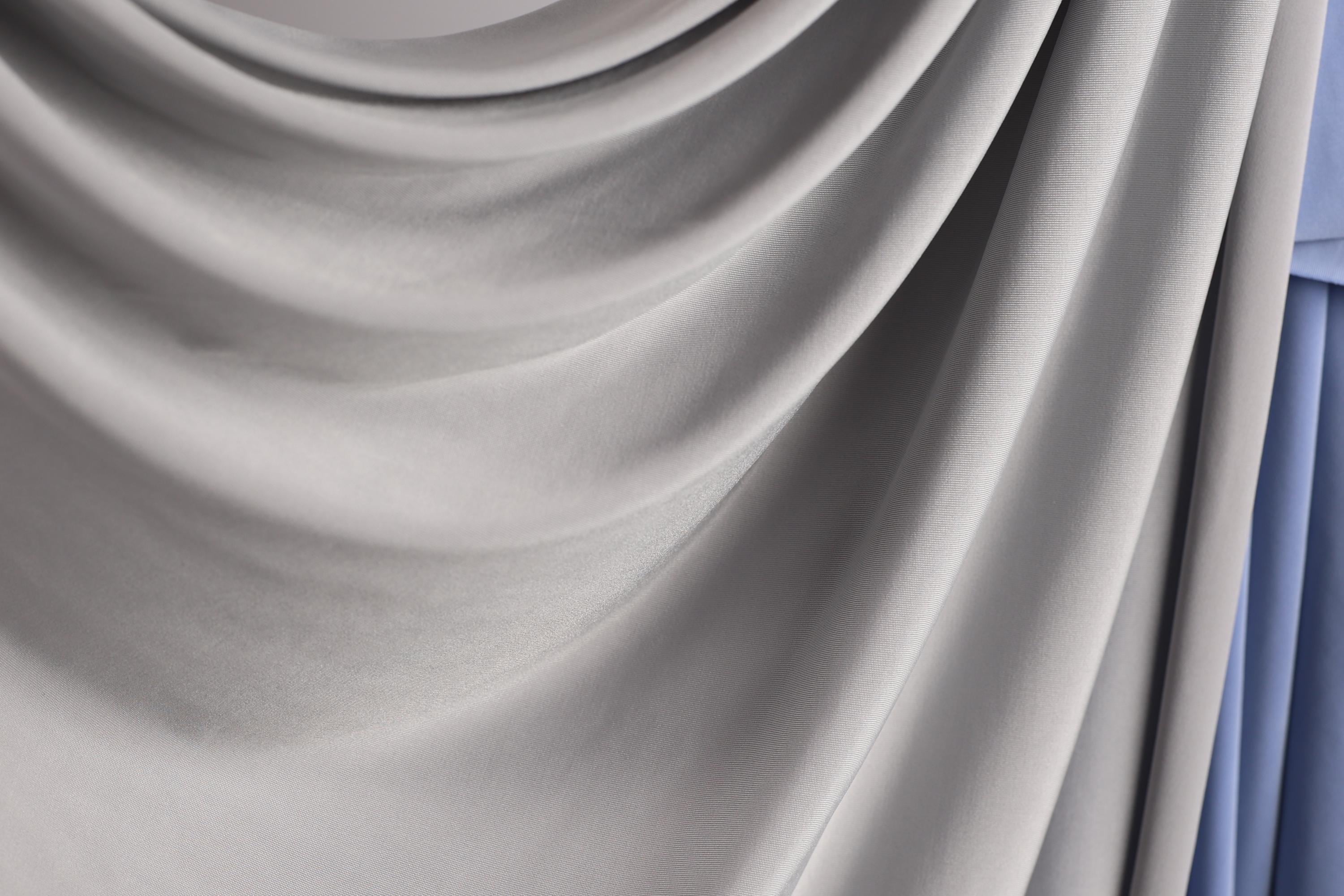a close-up view of a gray fabric, possibly a curtain or textile, with a soft, flowing texture.