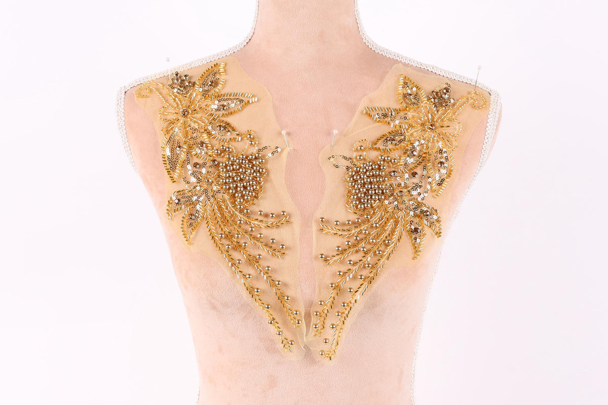 a mannequin with two gold embellishments on its bust, including flowers and leaves.