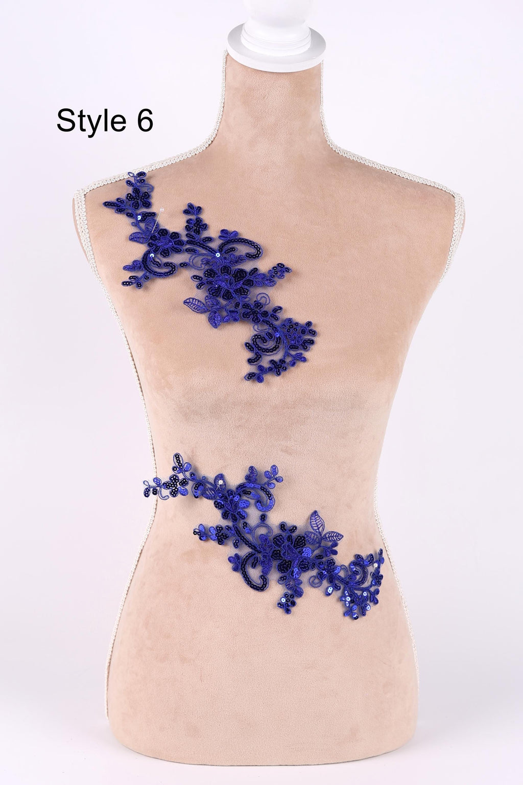 A mannequin wearing a beige dress with a decorative blue lace or sequin piece on the bust area.