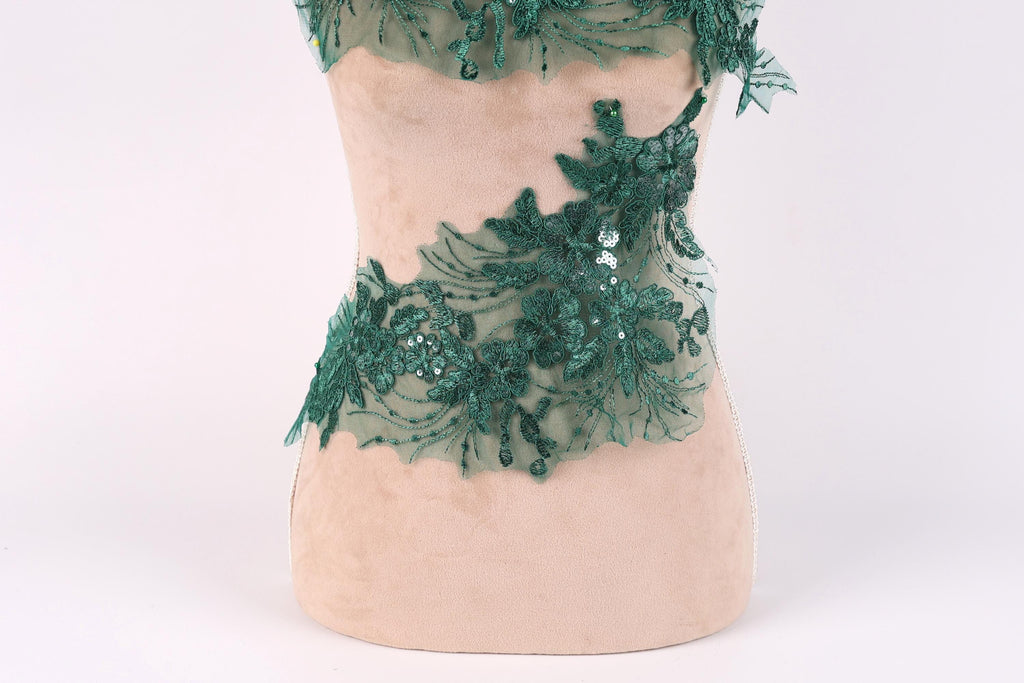 A mannequin wearing a dress with a green lace and sequin design.