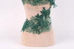 A mannequin wearing a dress with a green lace and sequin design.