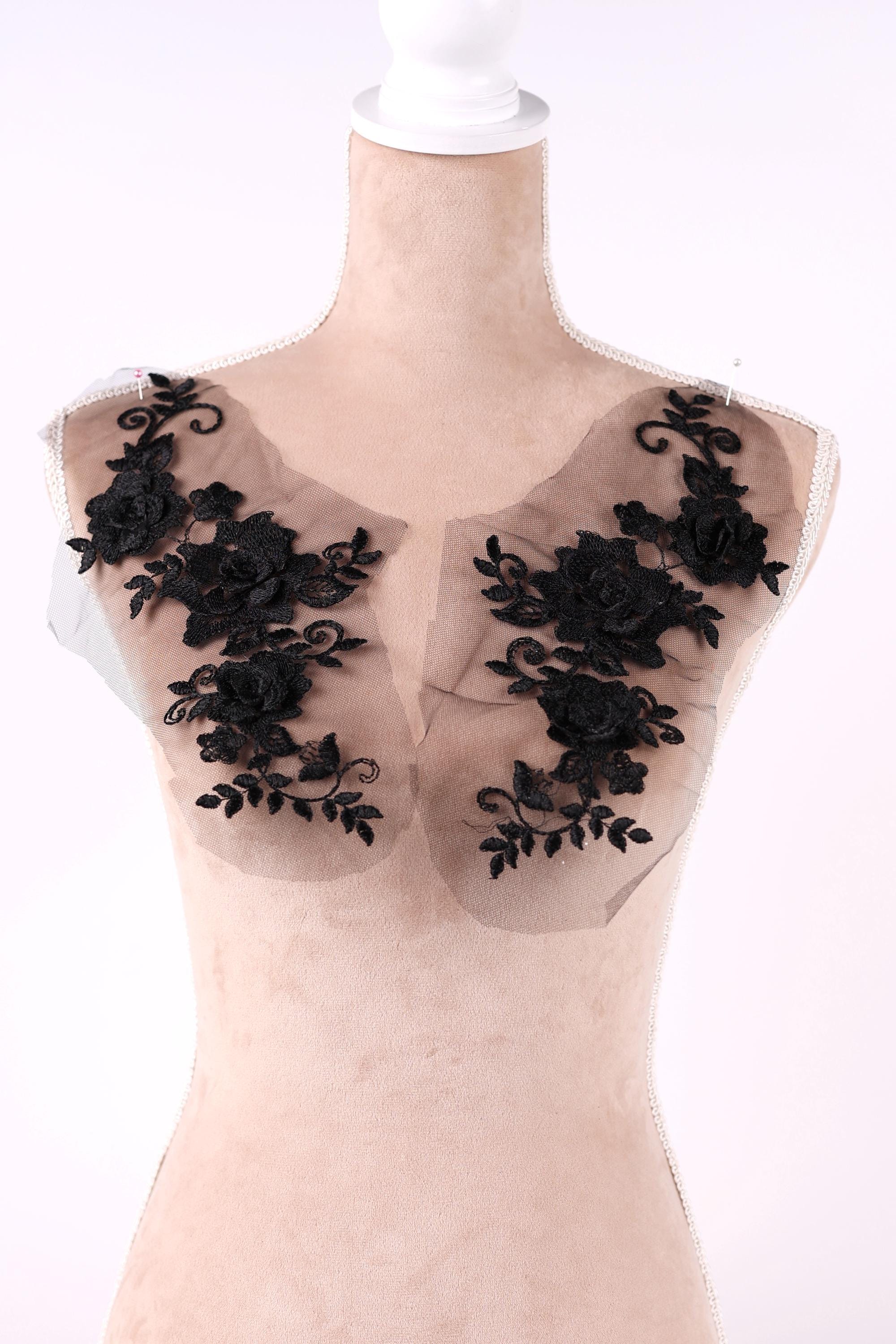 A mannequin with a beige body and black lace flowers on its shoulders.