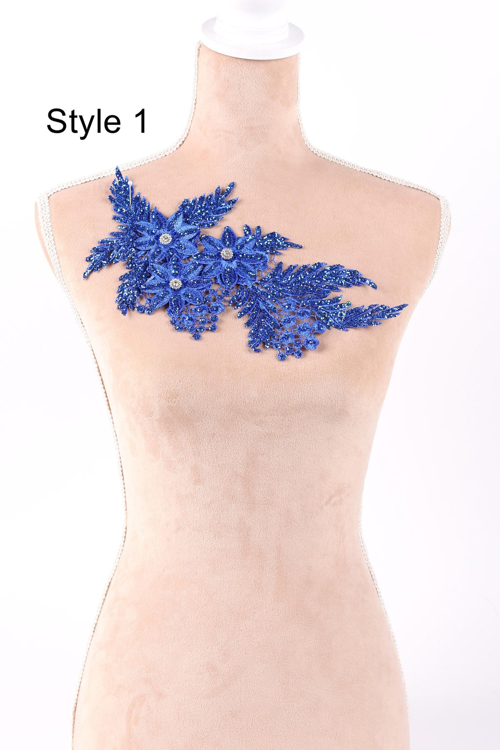 A mannequin wearing a dress with a blue floral embroidered patch on the shoulder.