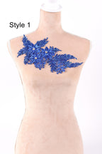 A mannequin wearing a dress with a blue floral embroidered patch on the shoulder.