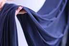 A hand is holding a piece of blue fabric, which appears to be a close-up view of the fabric.
