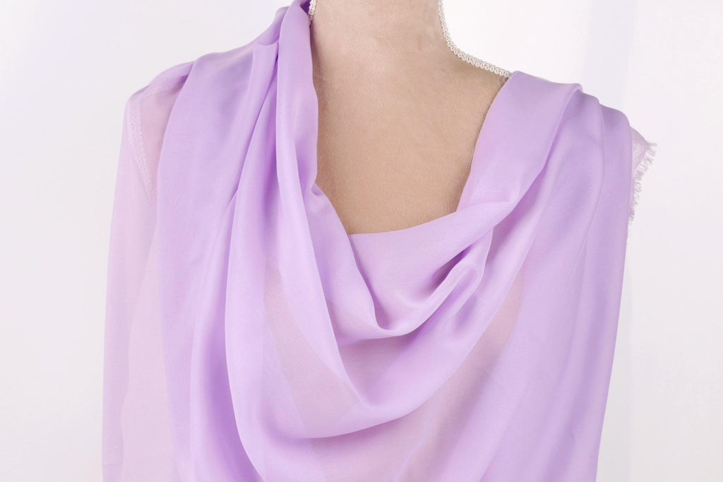 A mannequin wearing a lavender-colored, draped garment with a soft, flowing texture.