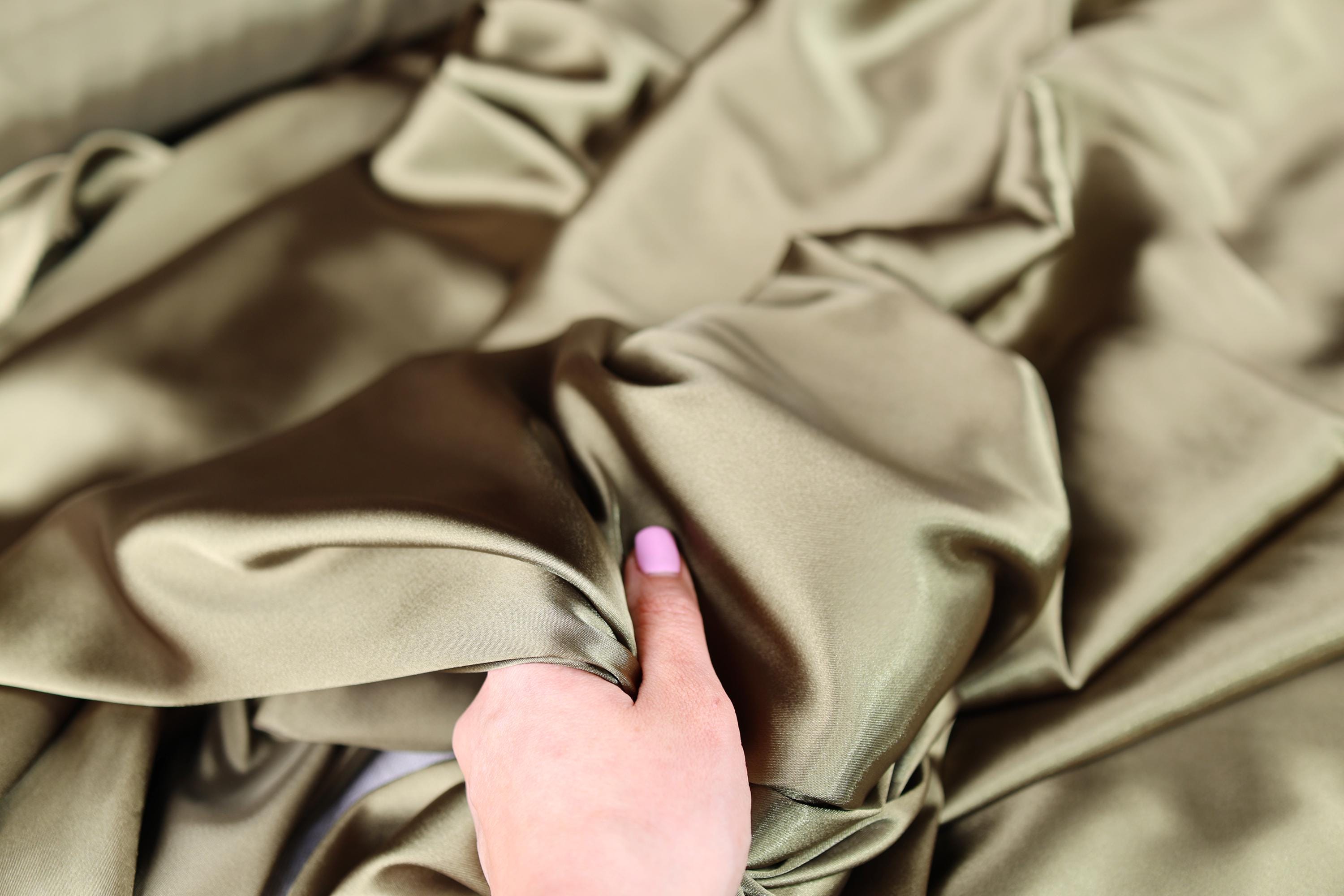 a person&#39;s finger on a satin material
