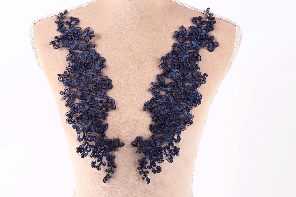 A mannequin torso wearing a dress with a long, intricate blue lace design on the neck area.