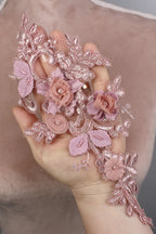 A hand adorned with delicate pink lace flowers and leaves, creating a beautiful and intricate floral design.