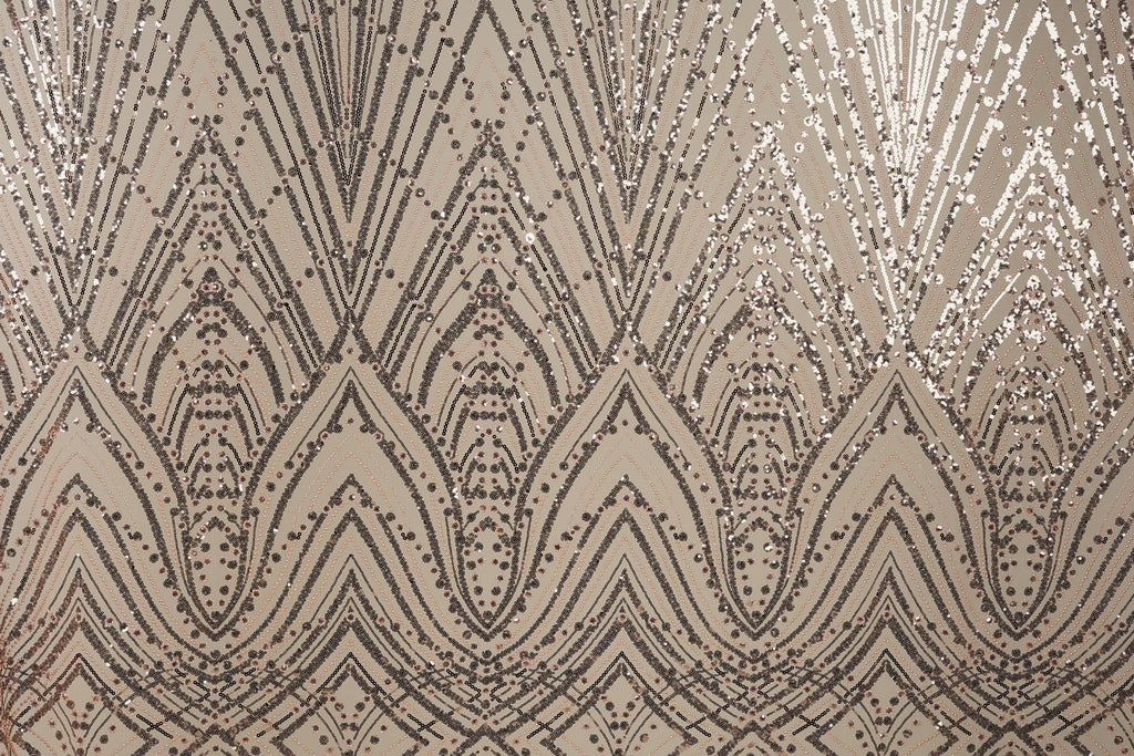 a close-up view of a fabric with a repeating pattern of diamond-shaped sequins in shades of brown and beige. The pattern is intricate and detailed, with the sequins arranged in a zigzag or diagonal pattern across the fabric. The overall appearance of the fabric is visually striking and textured, with the sequins adding a touch of sparkle and elegance to the design.