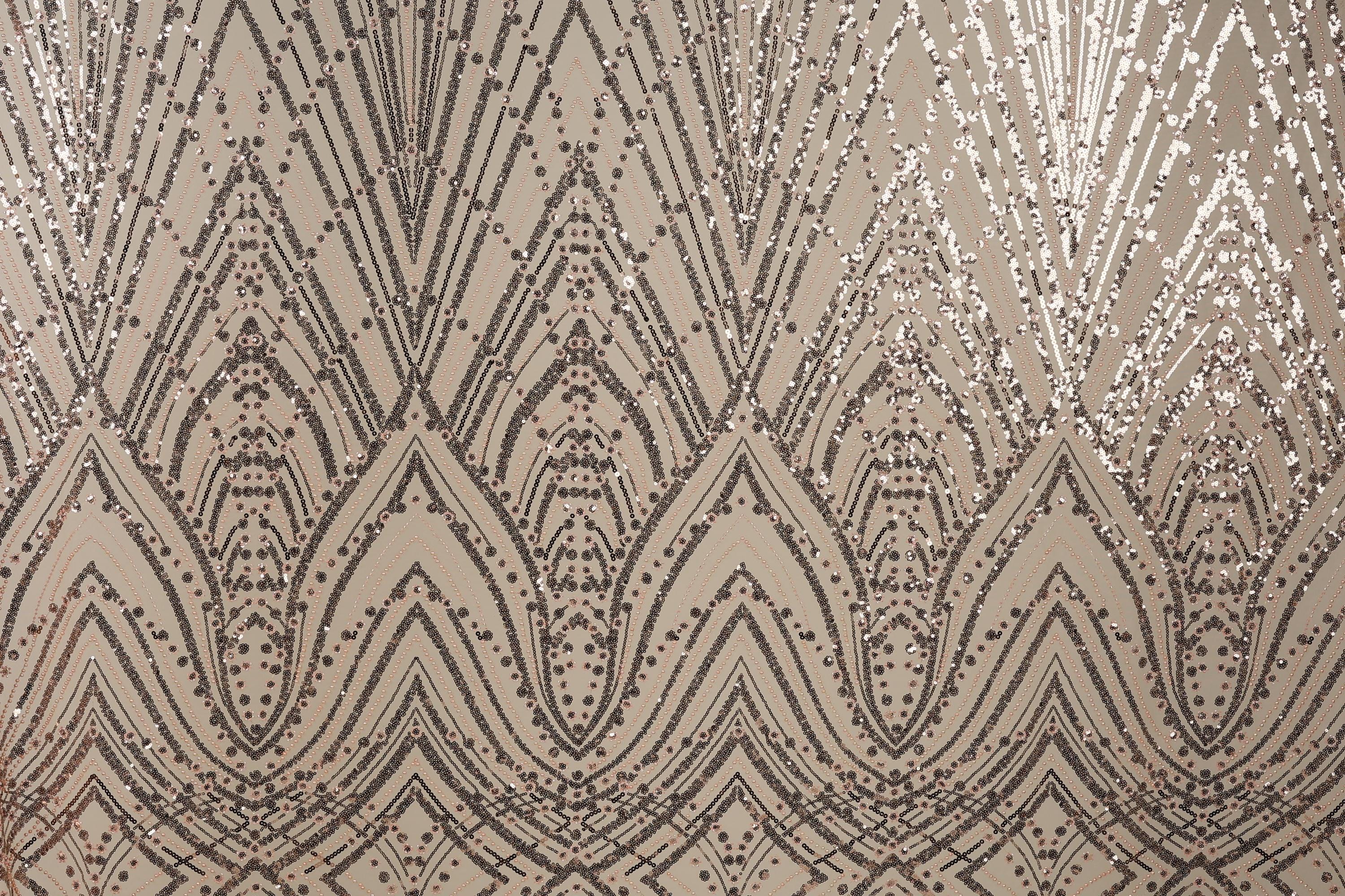 a close-up view of a fabric with a repeating pattern of diamond-shaped sequins in shades of brown and beige. The pattern is intricate and detailed, with the sequins arranged in a zigzag or diagonal pattern across the fabric. The overall appearance of the fabric is visually striking and textured, with the sequins adding a touch of sparkle and elegance to the design.