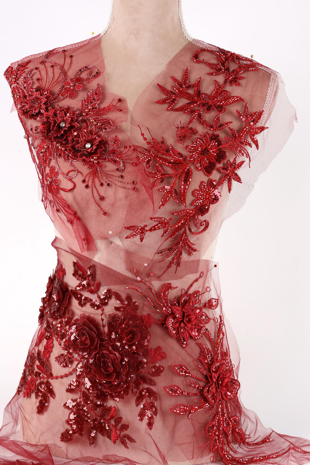 A mannequin wearing a red dress with intricate floral embroidery and sequin details.