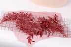 a close-up view of a delicate red floral embroidery on a piece of fabric, with a ruler placed on top of it to measure the size.