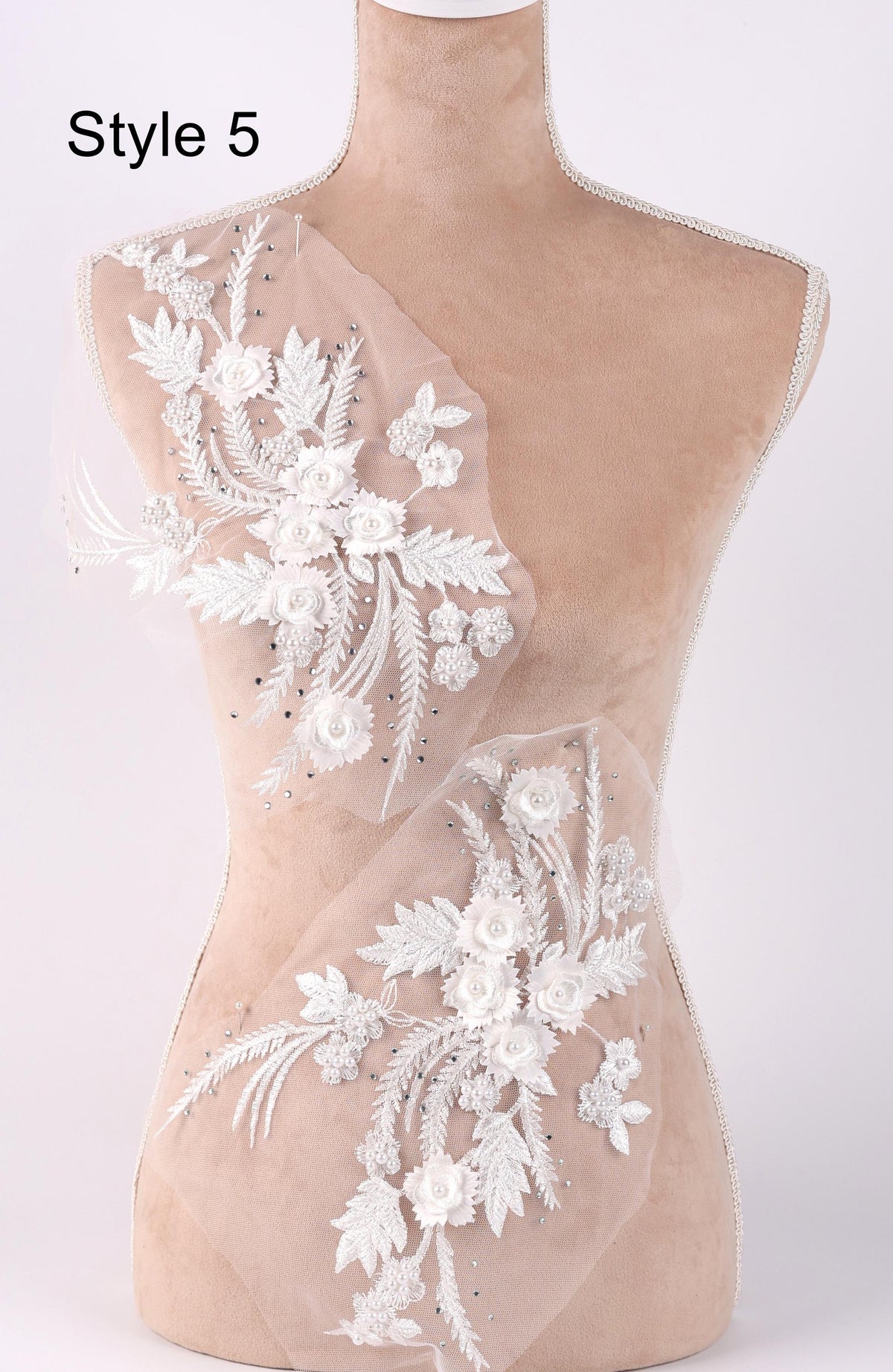 A mannequin with a dress form, wearing a white lace dress with floral embroidery.