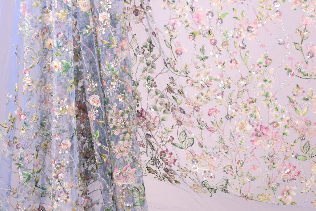 a close-up view of a delicate, floral-patterned fabric, with a blend of pink, green, and white colors. The fabric appears to be made of sheer material, giving it a soft and delicate appearance. The intricate floral designs and patterns on the fabric create a visually appealing and textured surface.