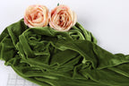 two pink roses resting on a crumpled green fabric.