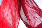 a close-up view of a red fabric, possibly a sheer or sheer-like material, with a textured and flowing appearance. The fabric appears to be made of a sheer or sheer-like material, which is characterized by its delicate and transparent nature. The fabric is slightly wrinkled, adding to its overall texture and visual appeal.