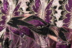 a close-up view of a fabric with a striking purple and black pattern, adorned with sequins and beads. The fabric appears to be a sheer material, with a floral design that adds a touch of elegance and sophistication to the overall appearance.