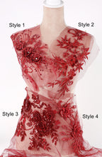 A mannequin wearing a red dress with intricate floral embroidery and sequin details.