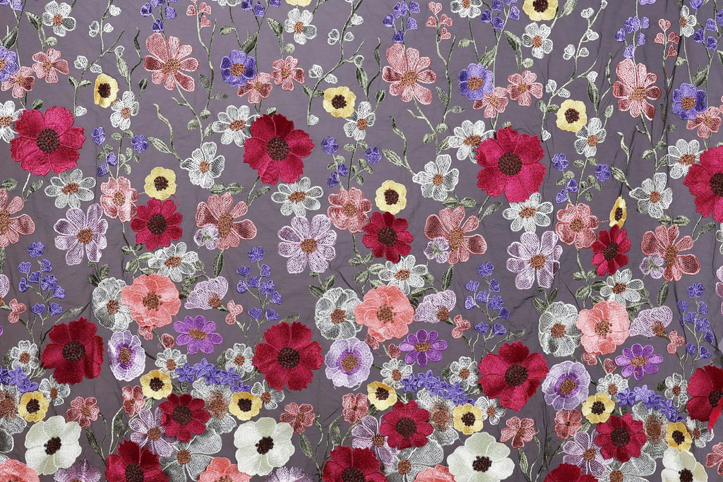 a vibrant and colorful floral pattern with a variety of flowers in shades of red, pink, white, and purple. The flowers are intricately embroidered or stitched onto a fabric or surface, creating a visually striking and detailed design.
