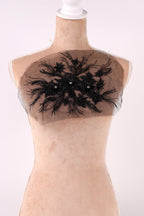 A mannequin wearing a dress with a black floral embroidered patch on the chest area.