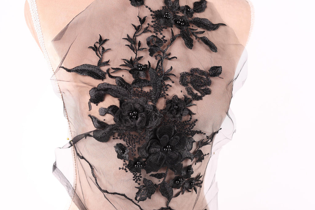 A close-up view of a delicate black lace fabric with intricate floral patterns.