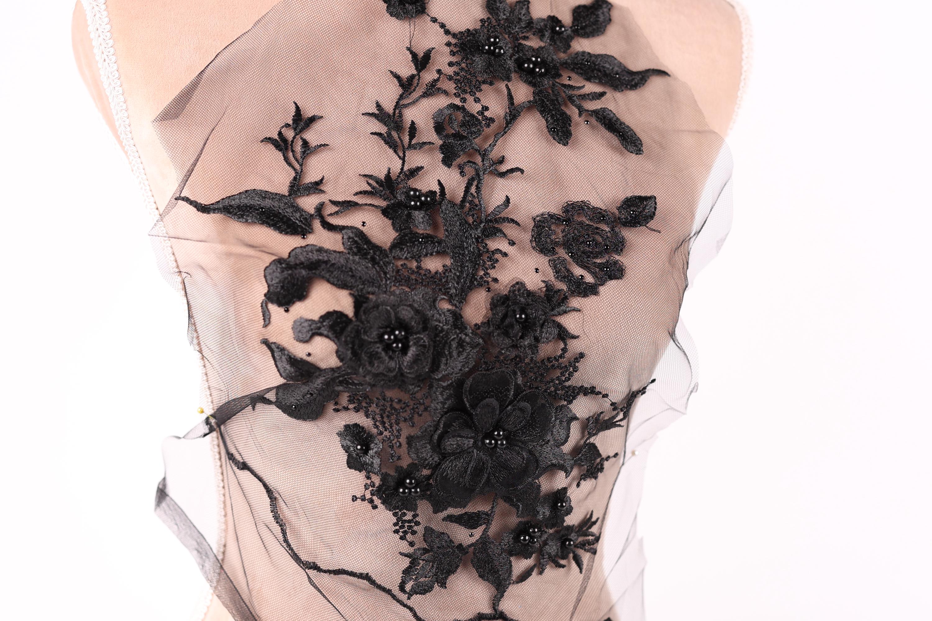 A close-up view of a delicate black lace fabric with intricate floral patterns.