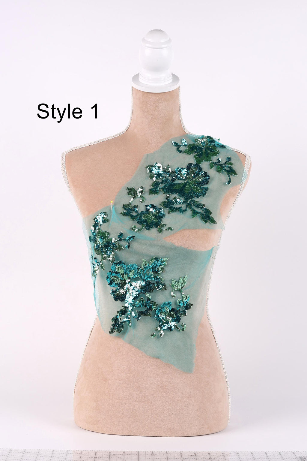 A mannequin with a light-colored body and a light-colored headdress adorned with green sequins.
