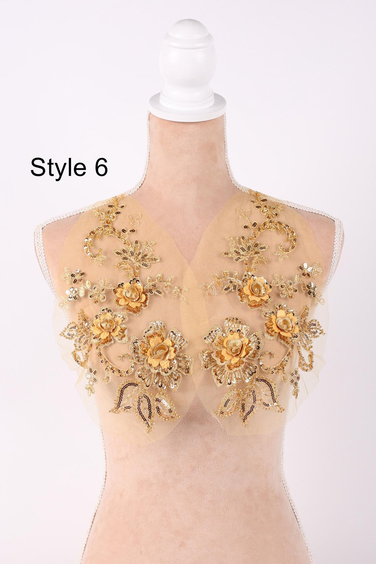 A mannequin wearing a gold and beige floral-patterned dress with a white headband.