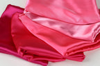 a close-up view of several pieces of pink satin fabric, with varying degrees of wrinkled texture.