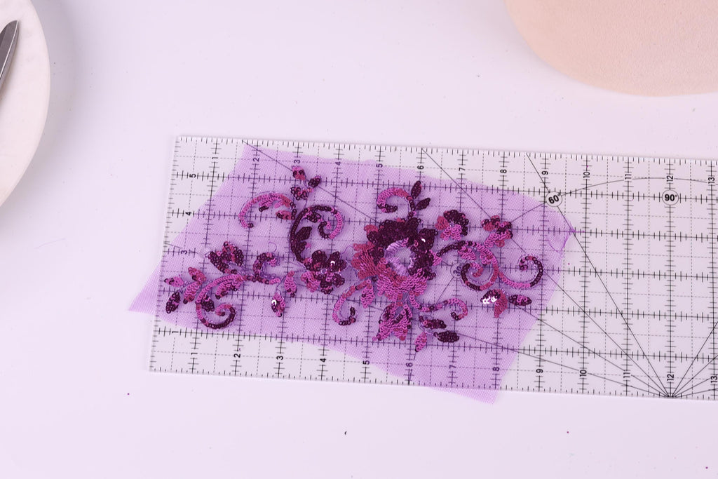 a clear ruler with a purple floral design on it, placed on a white surface.