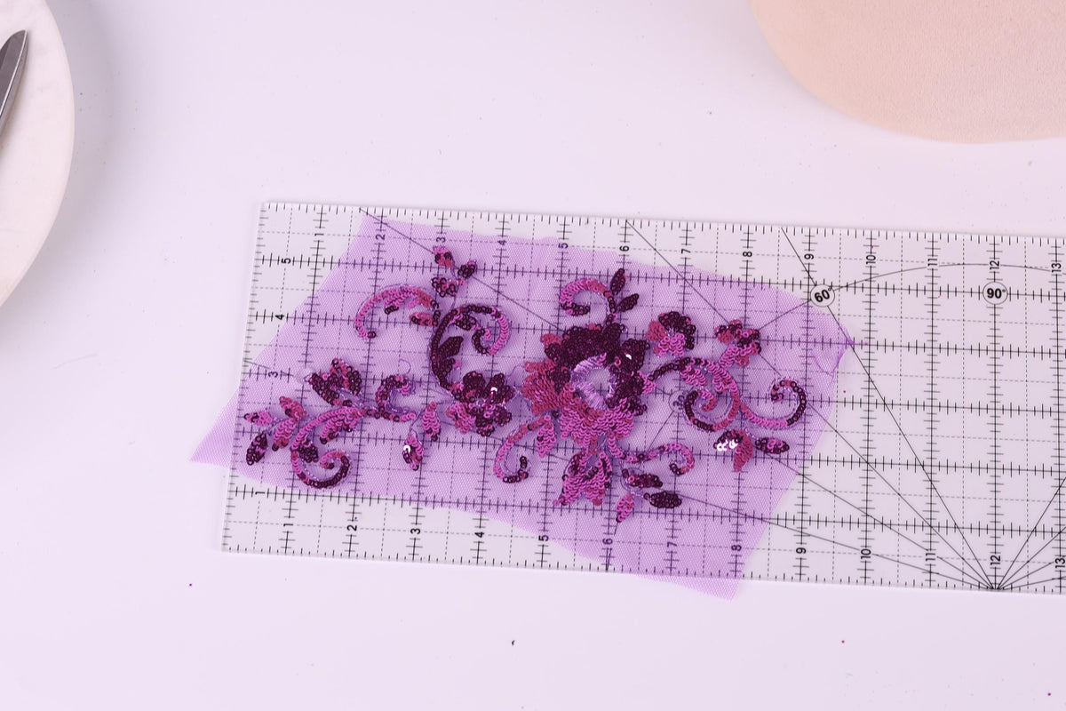 a clear ruler with a purple floral design on it, placed on a white surface.