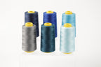 six spools of thread in various colors, including blue, gray, and light blue, arranged in a row.