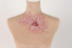 A mannequin with a pink floral embellishment on its neck.