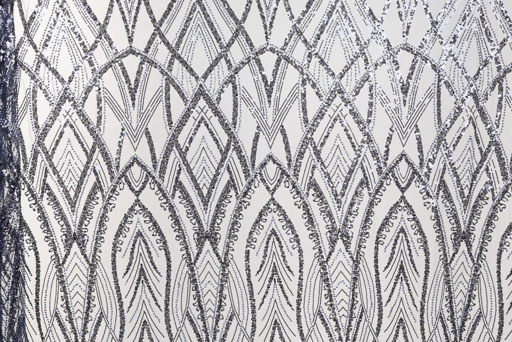 a close-up view of a fabric with a repeating pattern of diamond shapes in shades of black and white. The pattern is intricate and detailed, with the diamonds arranged in a diagonal line across the fabric. The overall appearance of the fabric suggests it could be used for decorative purposes or as a textile material.