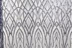 a close-up view of a fabric with a repeating pattern of diamond shapes in shades of black and white. The pattern is intricate and detailed, with the diamonds arranged in a diagonal line across the fabric. The overall appearance of the fabric suggests it could be used for decorative purposes or as a textile material.