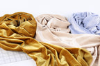 three crumpled fabric swatches in various colors, including gold, beige, and blue, arranged on a white background.