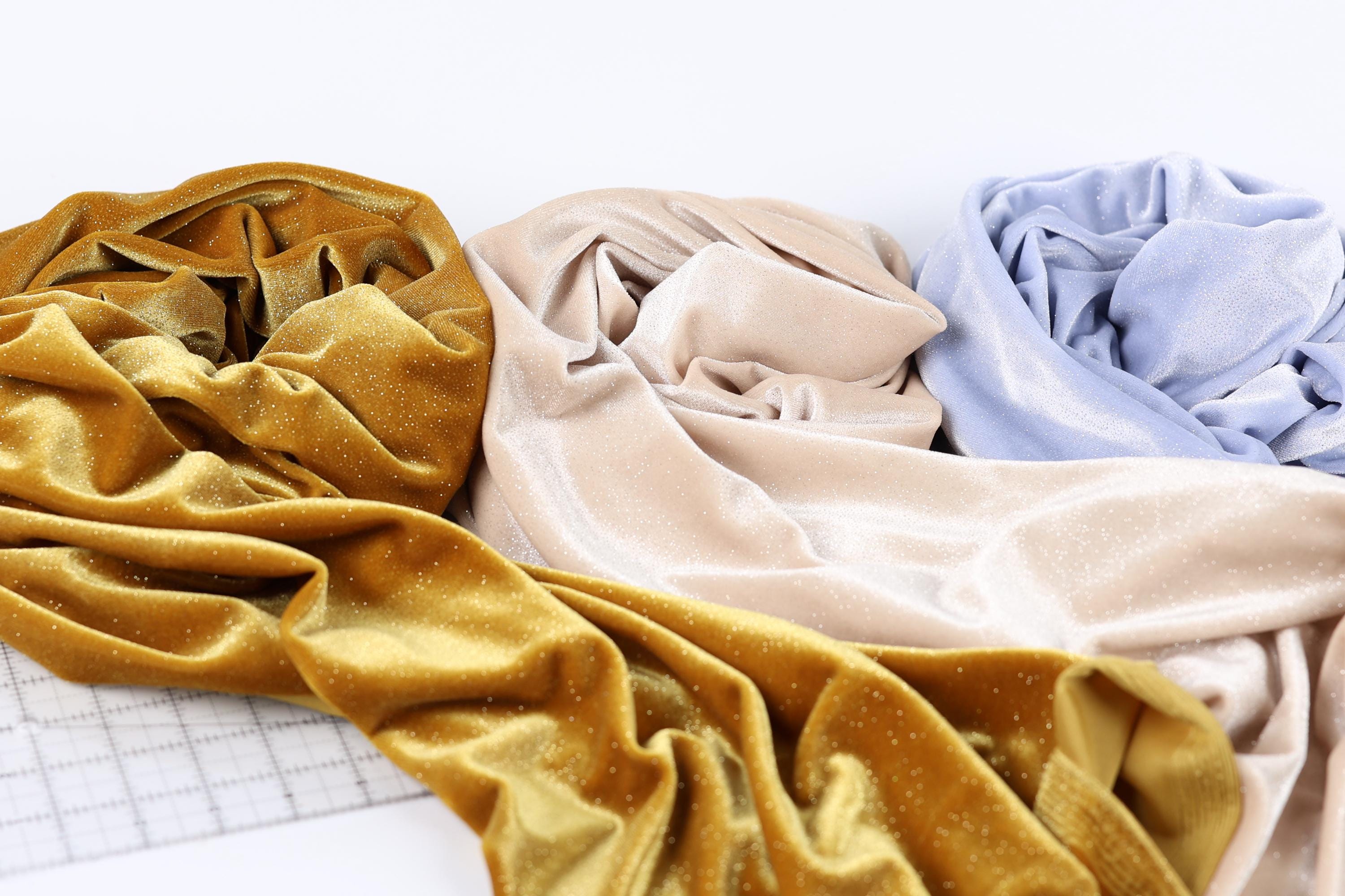 three crumpled fabric swatches in various colors, including gold, beige, and blue, arranged on a white background.