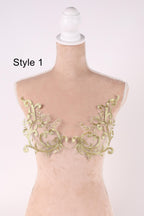 A mannequin with a white head and a beige body, wearing a bra with gold embroidered floral patterns.